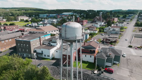 Orbiting-Aerial-Shot-Showcases-Madawaska,-Maine-Water-Tower,-Main-Street,-and-Church