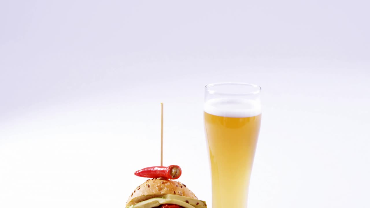 hamburguesa y un vaso de cerveza contra un fondo blanco