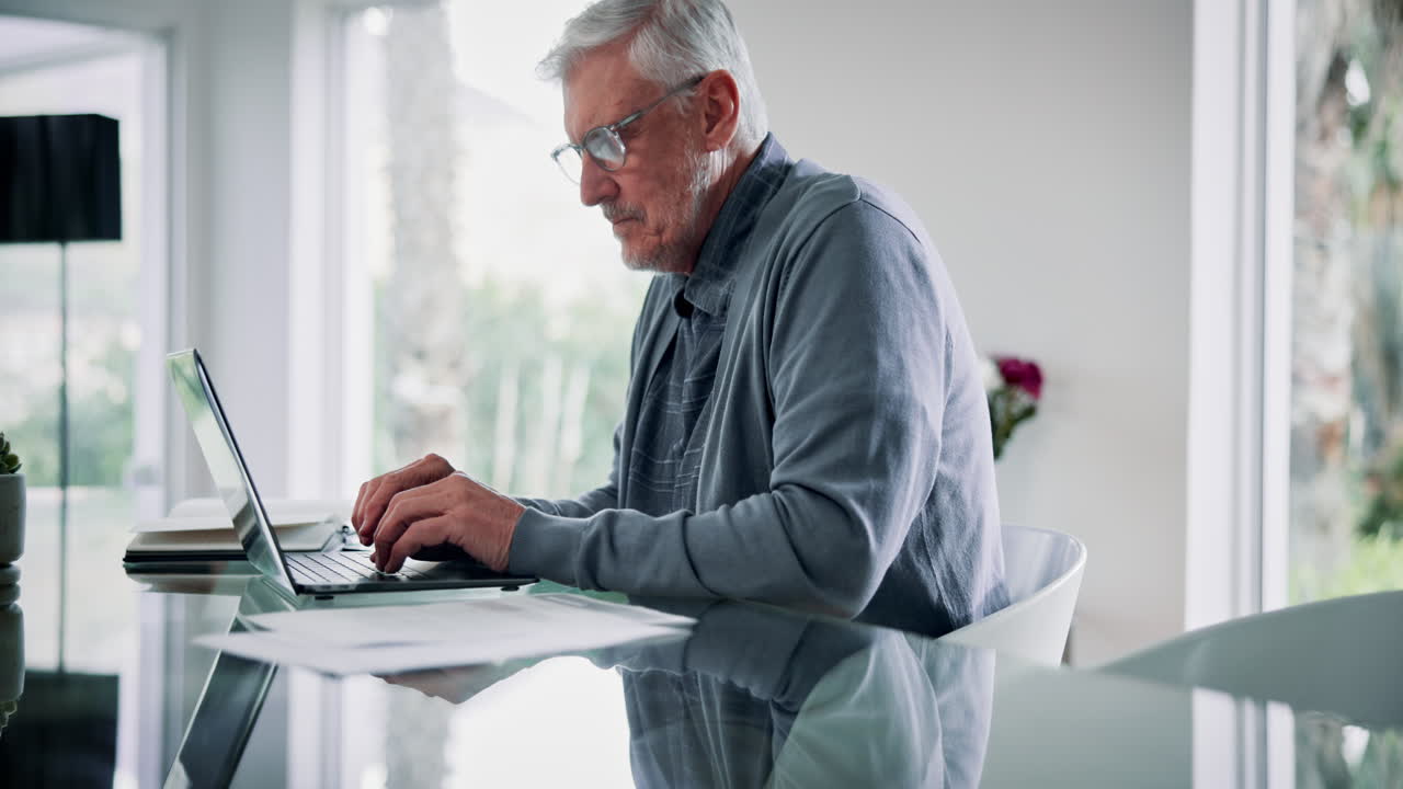 Elderly Man with Back Pain Working at a Laptop