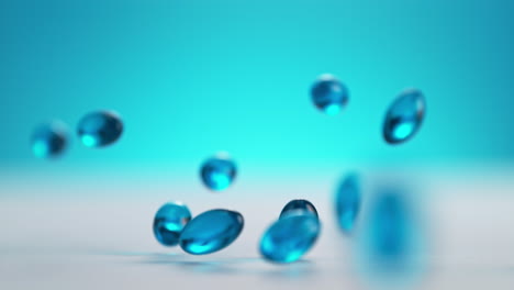 las cápsulas de gel blando azul caen sobre una mesa blanca y rebotan en cámara lenta y macro sobre el fondo azul