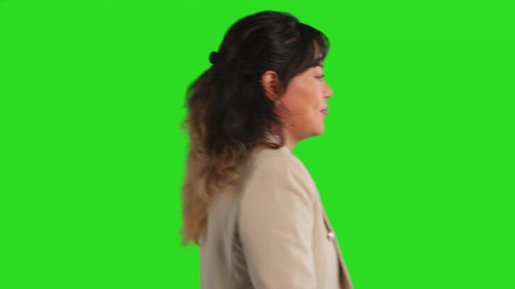 Close Up Studio Profile Shot Of Female Teacher Or Businesswoman Walking Past Green Screen