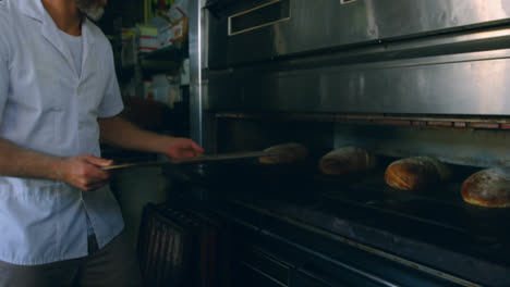 male chef removing bread from oven 4k