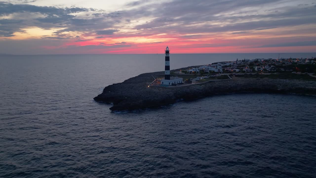 Lighthouse glowing, Aerial Drone fly Sunset sky in Menorca Landscape Over Cap d’Artrutx, Mediterranean Skyline