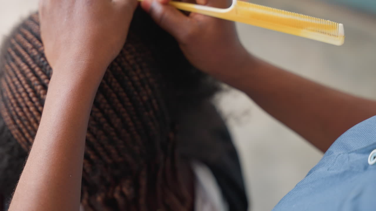 Sessione di districatura e styling dei capelli. Primo piano delle tecniche di finitura delle trecce e pettinatura delle radici. Tecnico professionista dei capelli che districa e acconcia meticolosamente le trecce per un aspetto curato.