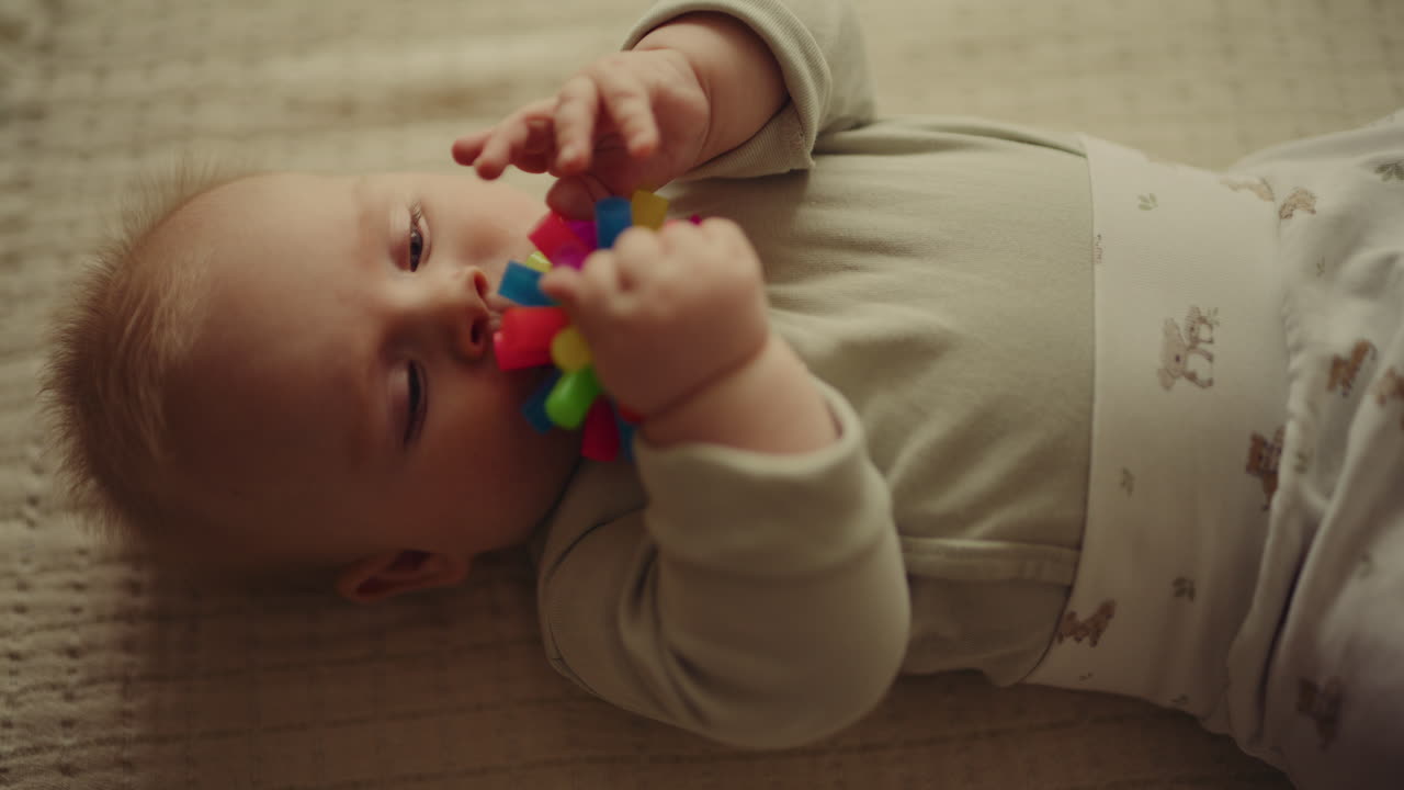 Baby Boy Chewing Rubber Toy on Blanket