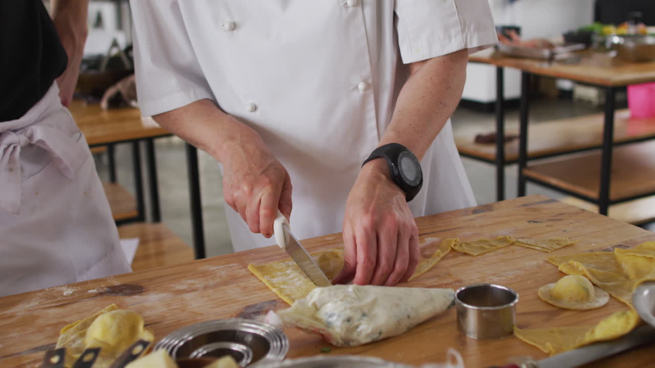 cocinera caucásica enseñando a un grupo diverso preparando platos y sonriendo
