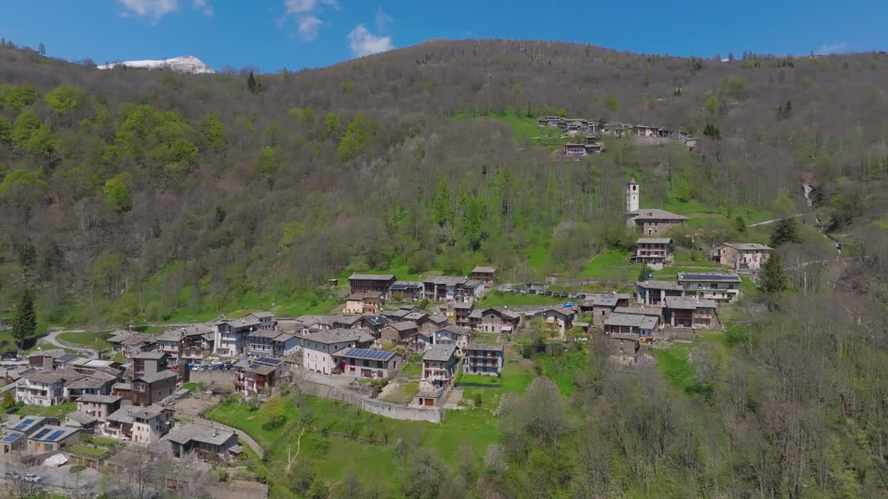 Stunning aerial panorama over a small, rustic settlement nestled in a lush mountainous valley