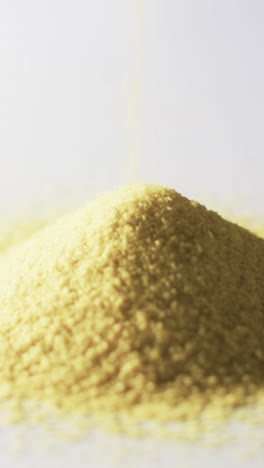 vertical video of close up of heap of yellow sand grains and copy space on white background