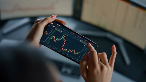 person analyzes financial charts on a smartphone