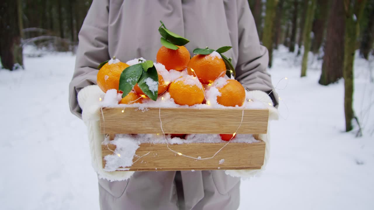 눈 인 오렌지 로 가득 찬 나무 상자를 들고 있는 여자