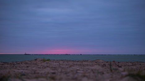 timelapse shot of blue and red sky over the sea just after sunset along the shoreline during evening time