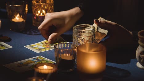 primer plano de una mujer dando lectura de cartas del tarot en una mesa a la luz de las velas sosteniendo la carta del mundo