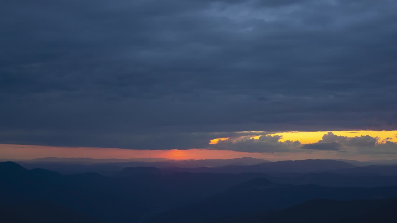 해가 지는 배경에서 산 위의 구름 흐름. 시간 지연