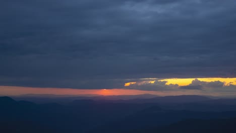 the cloud stream above mountains on a sunset background. time lapse