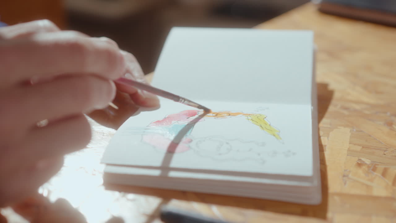 Artist Coloring Drawing on Paper with Watercolor Paints