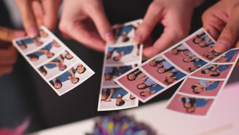 close up of a group of friends having fun looking at prints from photo booth with props 5