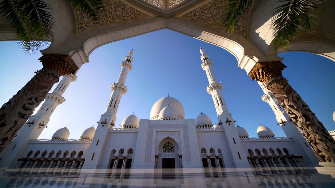 Video con angolazione dal basso di una grande moschea con archi e minareti decorati su un cielo azzurro