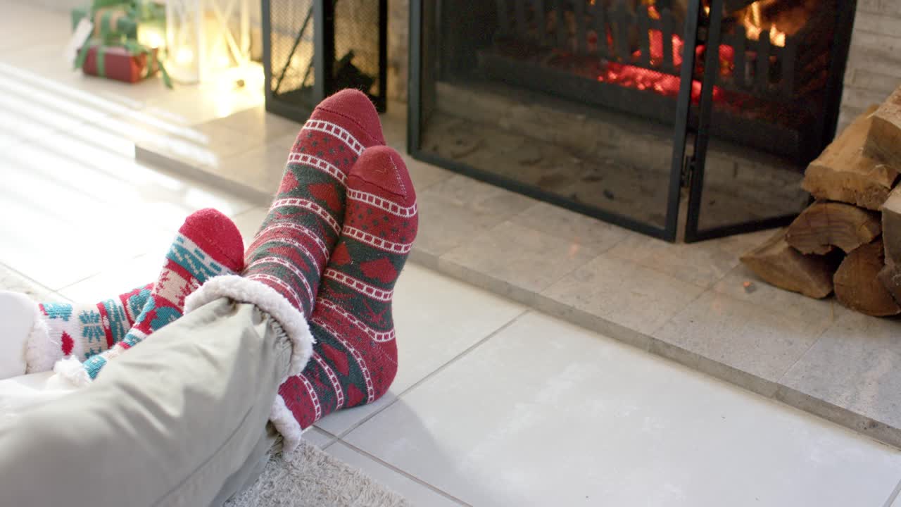 Con il fuoco che scoppietta, genitore e figlio si scaldano i piedi sul focolare piastrellato per un comfort festivo