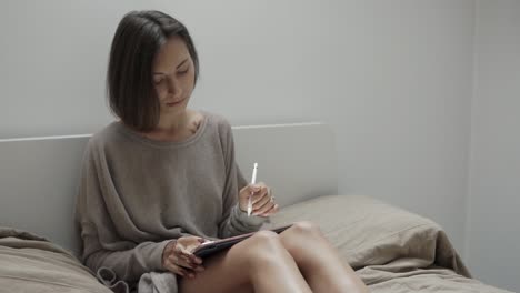 woman drawing on a tablet in bed