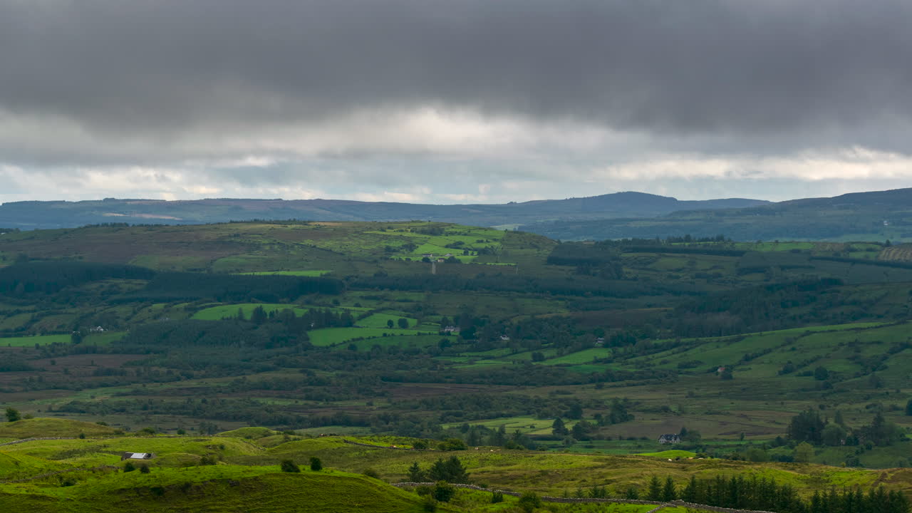 시골 아일랜드에서 흐린 극적인 날에 언덕과 들판이 있는 시골 풍경의 시간 경과
