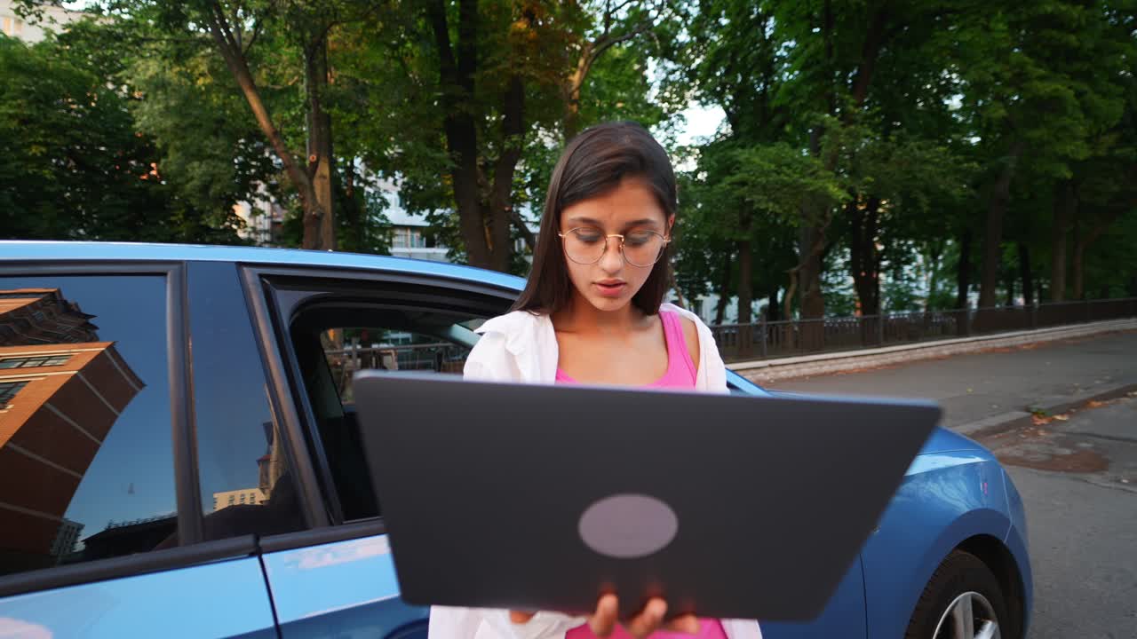 Young Woman Working on Laptop by a Car