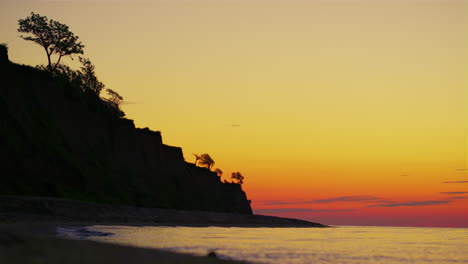 Rock-mountain-silhouette-with-trees-at-golden-sunrise-dusk.-Summer-landscape-sea