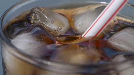 macro close up of a plastic straw being placed into an ice cold drink