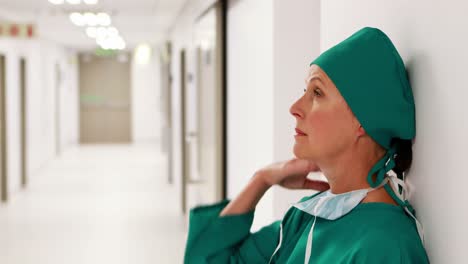 Tensed-female-surgeon-standing-in-corridor