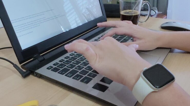 Mani di uno sviluppatore che digitano meticolosamente codice su una tastiera di laptop