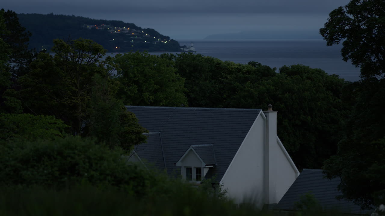 숲 속에 있는 현대적인 집의 일부, 나무로 둘러싸인 새로 지은 주택, 배경에는 안개가 가득한 어두운 바다, 밤이 지나고