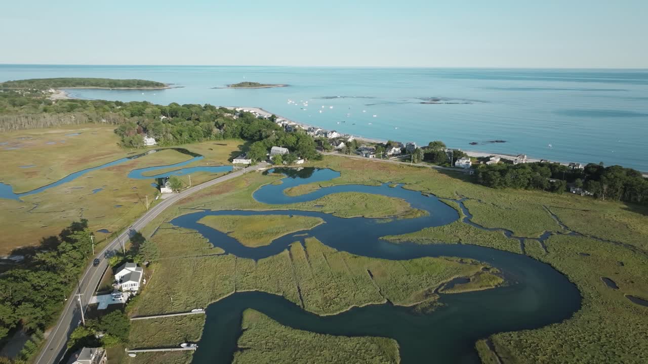Aerial view of tidal marshes in Kennebunk, Maine, with winding waterways, beachfront homes, and the Atlantic Ocean stretching out under clear skies.
