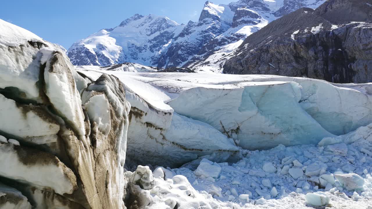 Morteratsch Glacier, ice formations, crevasses, moraine, sunny day, Swiss Alps, Climate change, Switzerland. Aerial backward tilt-up reveal