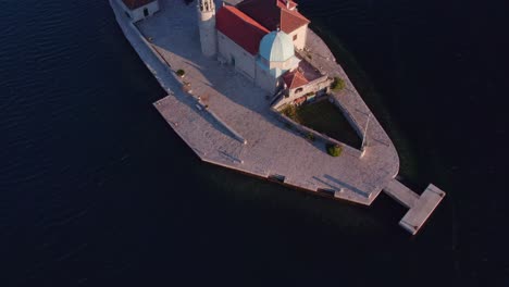 top down shot of holy church of our lady of the rocks in kotor bay during sunrise, aerial