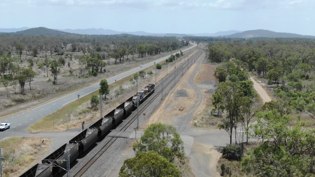 tren de carbón vacío que circula por el ferrocarril paralelo a la carretera, bajool en queensland, australia