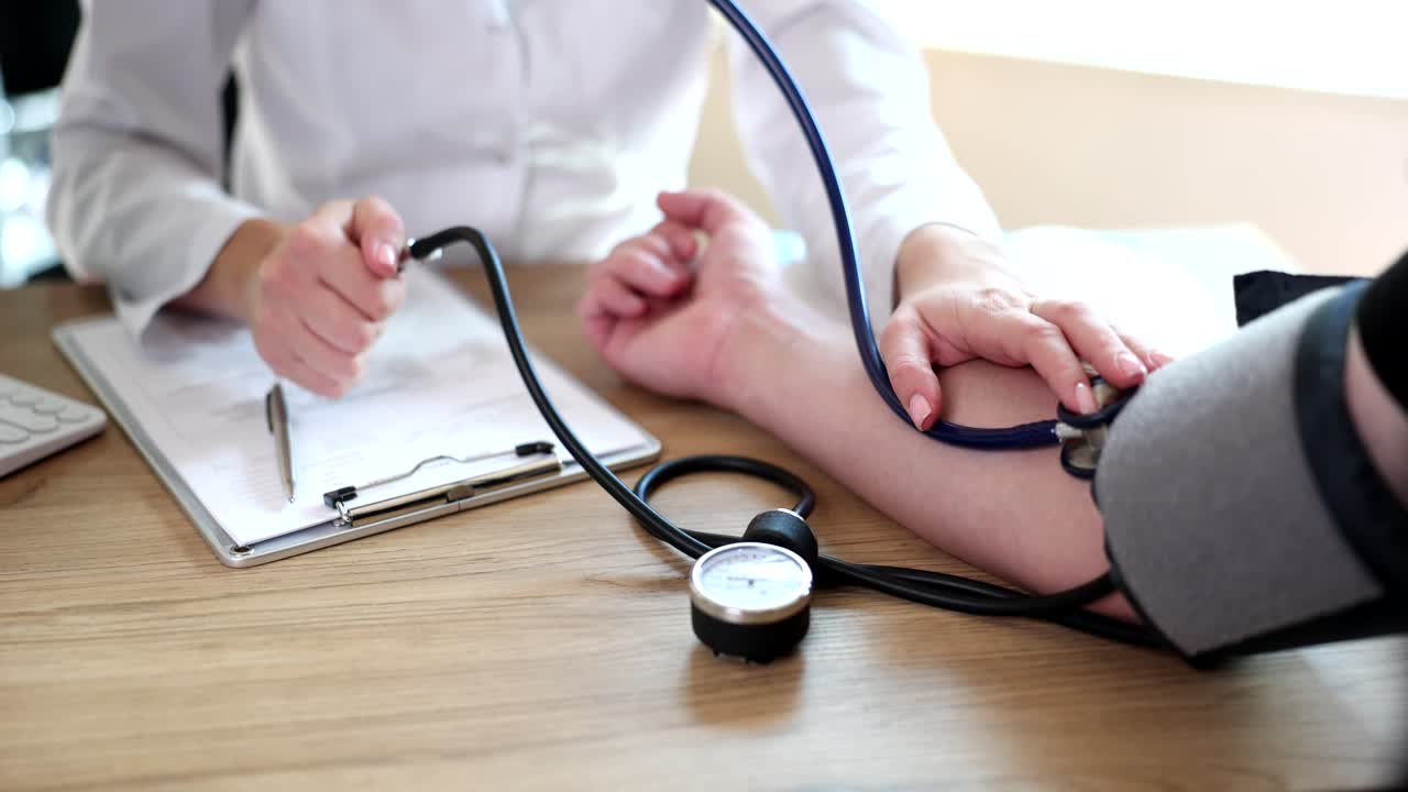 Cardiologo misura la pressione sanguigna a un paziente uomo con uno sfigmomanometro.