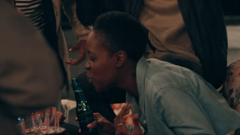 group of diverse friends celebrating birthday party on rooftop at night beautiful young african american woman blowing candles enjoying friendship having fun sharing celebration