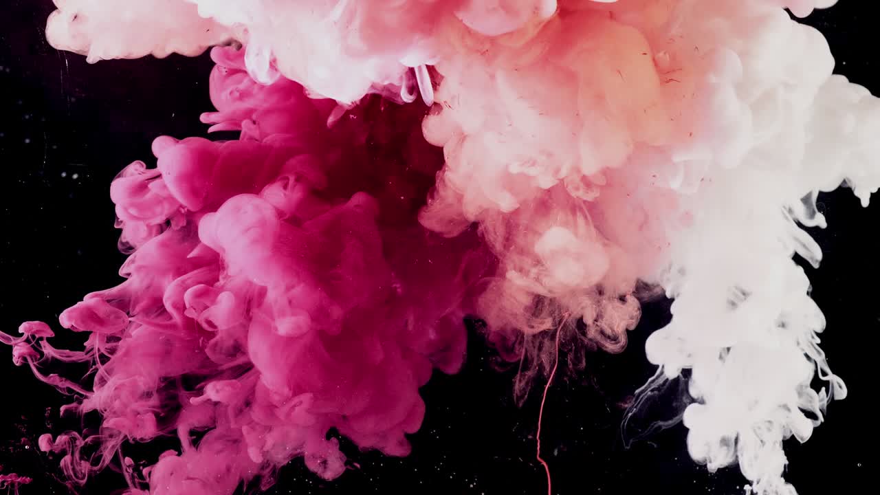 Color splashes of ink isolated on black background. Abstract paint in water, photographed in motion. Swirling colorful drops cloud.