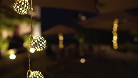 detalle de bolas de luz decorativas colgando y brillando en un jardín por la noche