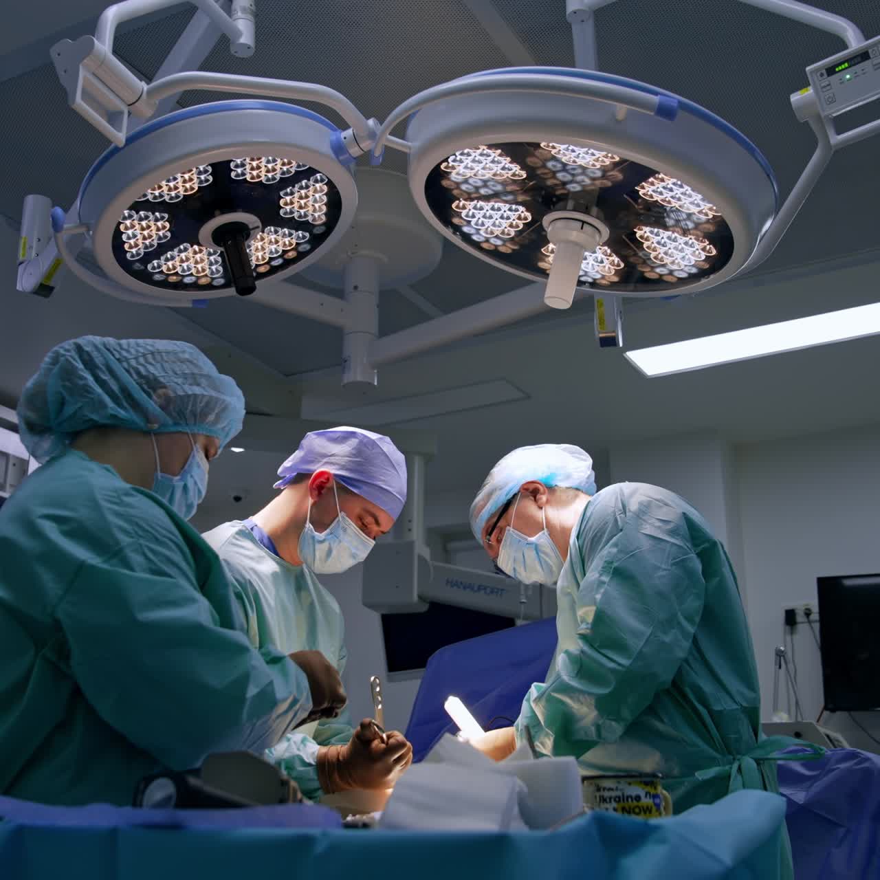 Approaching the operational table with a patient under surgery. Surgeon uses metal tool and nurse cleans it
