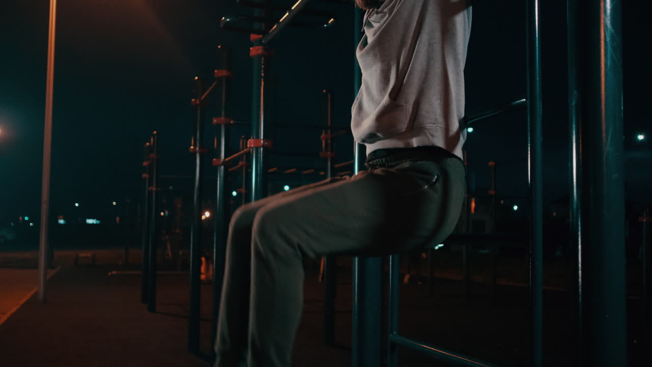 hombre haciendo pull-ups por la noche