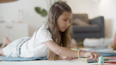 Cute-Girl-Lying-On-Floor,-Drawing-Picture-With-Colored-Pencils