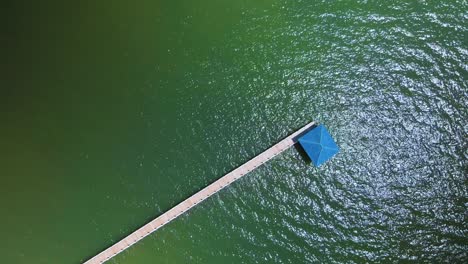 simple calm clean walking pier to huts jetting out into the blue green ocean rippling waves