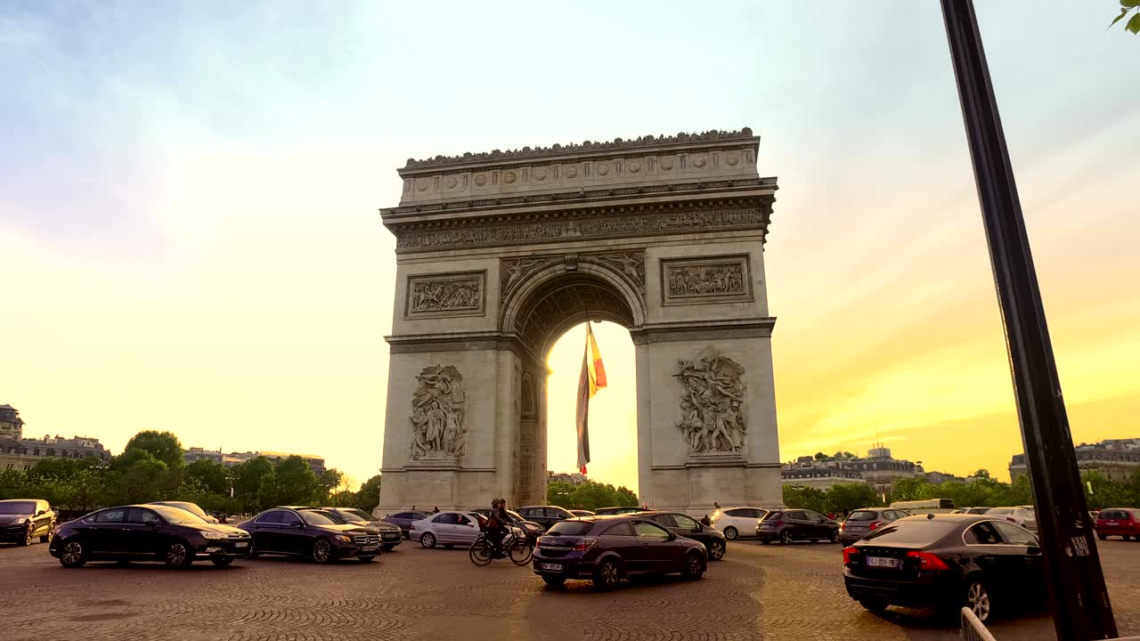 el arco del triunfo (arco de triunfo) al atardecer con coches y autobuses pasando, vista cinematográfica