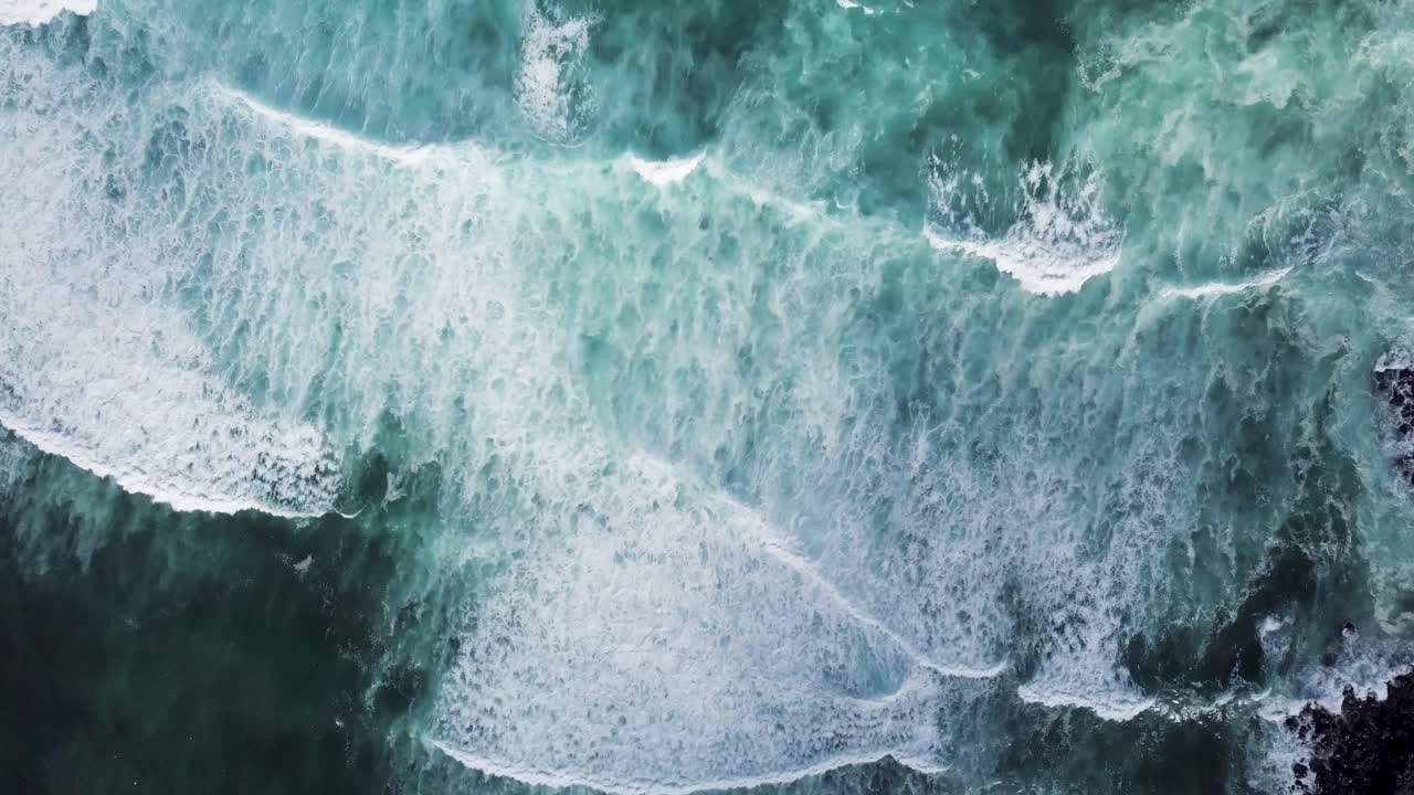 Powerful and symmetrical waves crash on the black sand shores of Maui, Hawaii