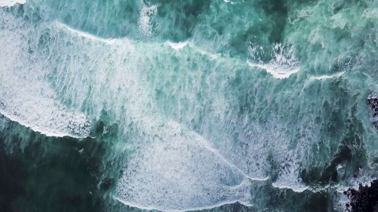 Powerful and symmetrical waves crash on the black sand shores of Maui, Hawaii