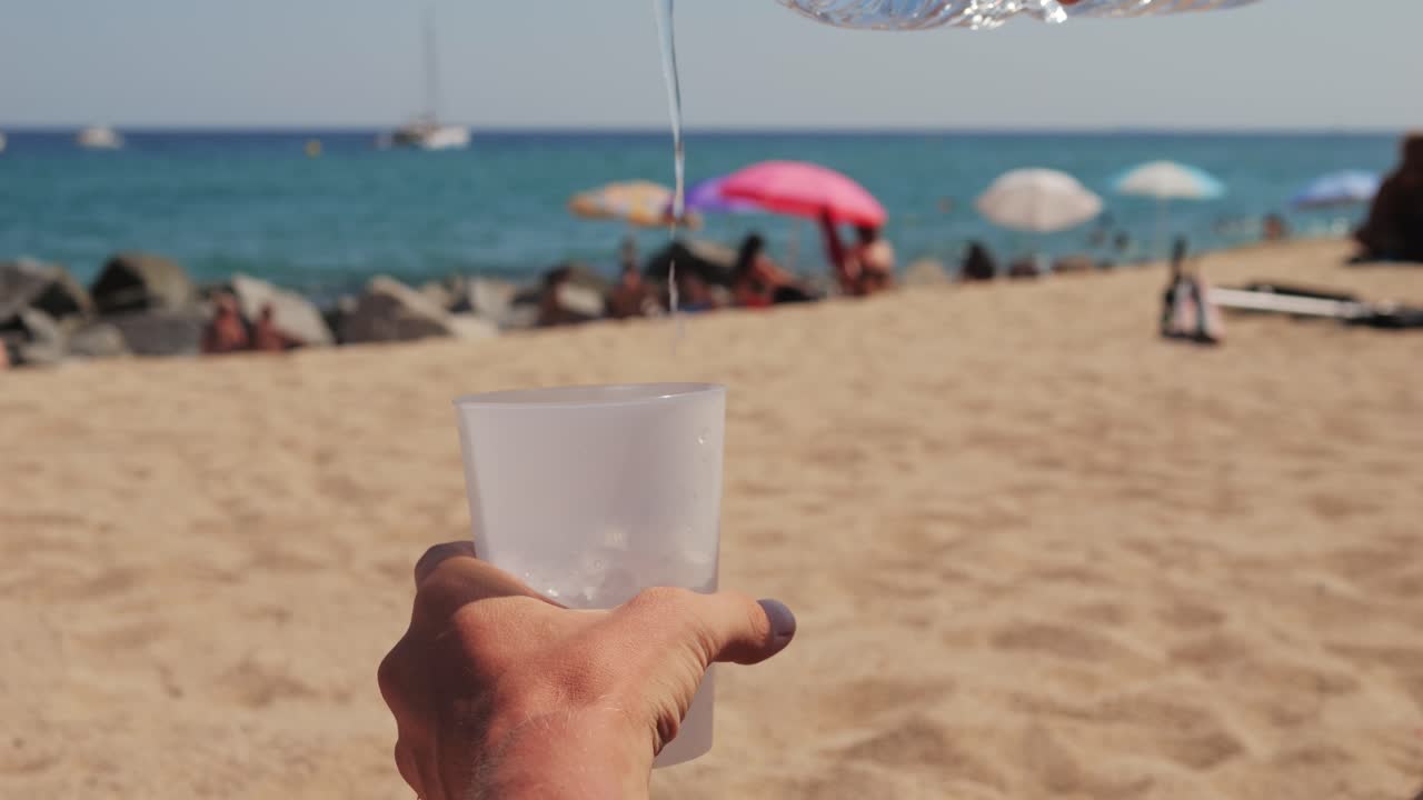 Pouring water into a glass on a beach