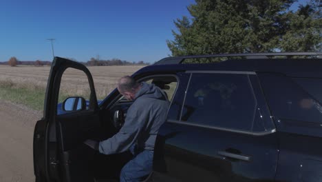 Man-closing-vehicle-hood-and-driving-away