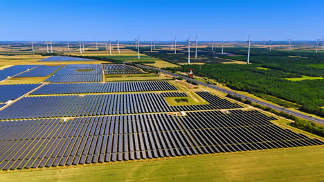 highway crosses the vast nature landscape in the countryside. aerial perspective on the solar panels site and wind farms