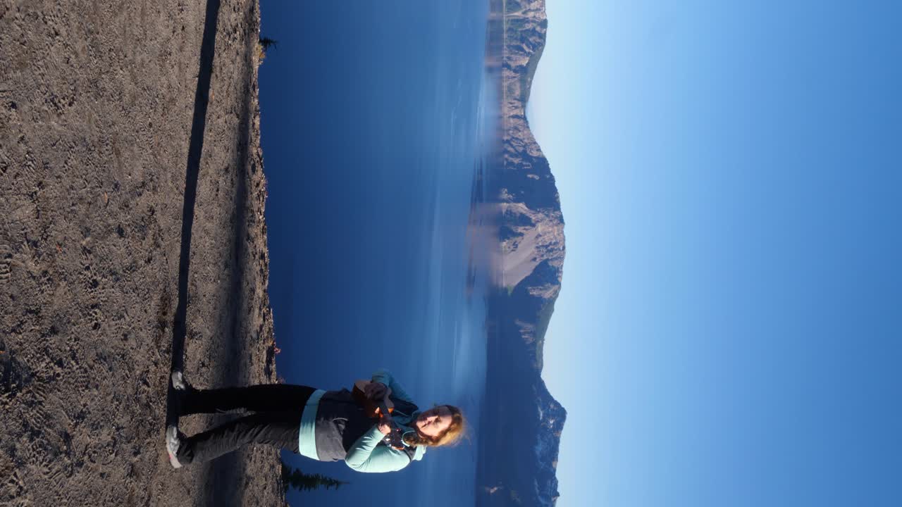 mujer pelirroja baila con vistas al parque nacional del lago del cráter mientras toca el ukelele