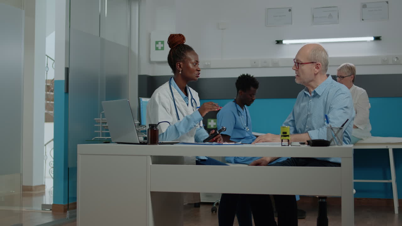 Dokter Afrika-Amerika memegang otoskop medis pada pria tua